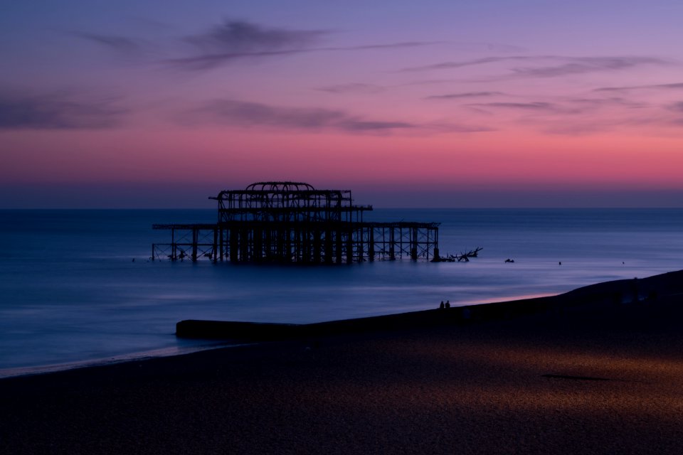 silhouette of structure at shore during sunset