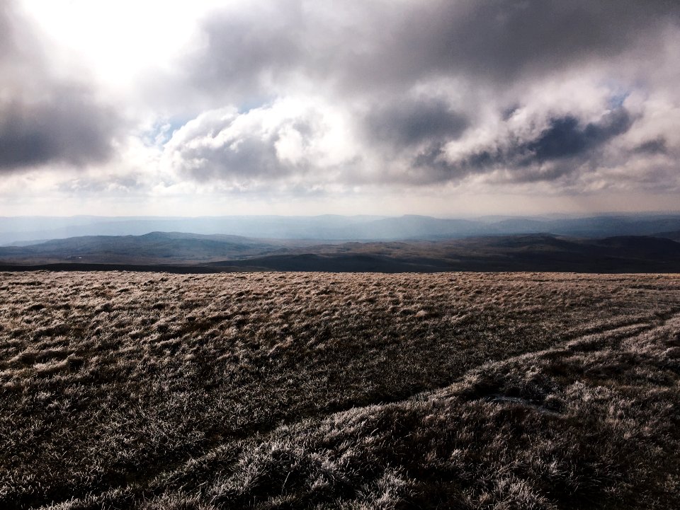 brown grass field near mountain under gray clouds