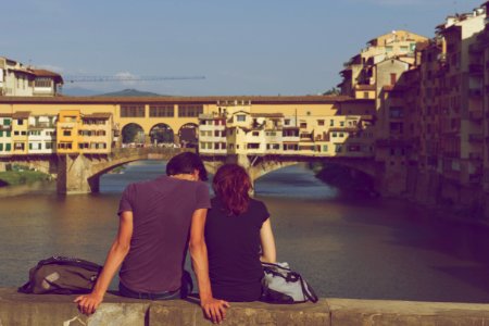 man and woman sitting together in front of body of water during daytime photo
