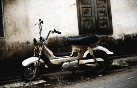 grey moped motorcycle park near wall photo