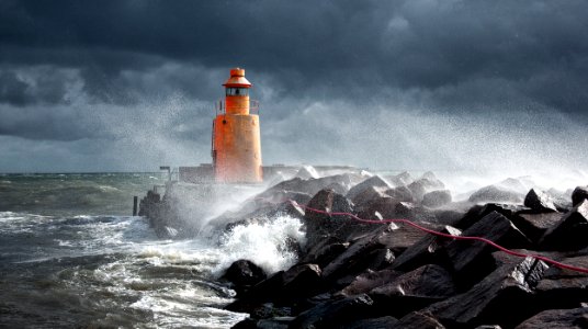 orange lighthouse on rock photo