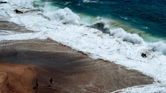 two person on seashore facing ocean waves photo