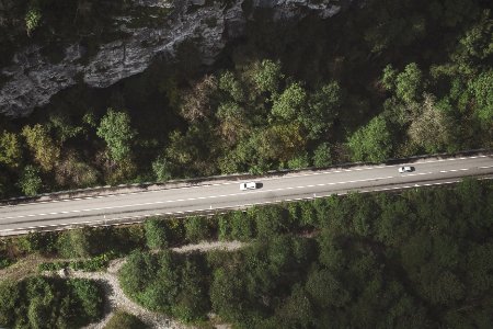 aerial photo of gray concrete in the middle of forest with two cars photo