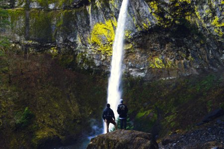 two persons standing on rock near waterfall at daytime photo
