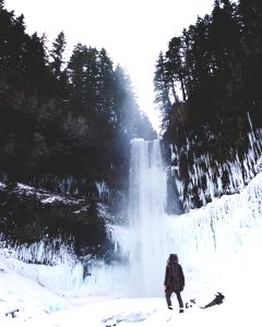 person standing looking at water falls covered by snows photo