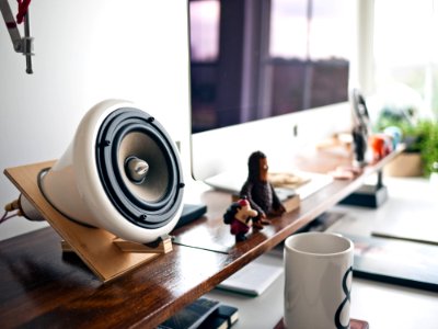 white speaker in brown holder beside silver Imac photo