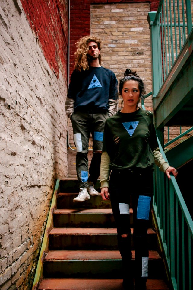 A young woman and a young man walking down the stairs in an old brick stairwell
