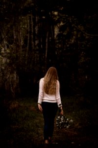 woman wearing white sweater and black pants walking near trees photo