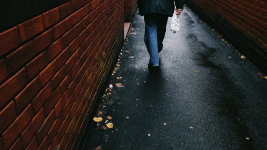person walking on black-paved alley photo
