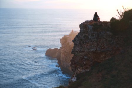 woman sitting on rock near cliff photo