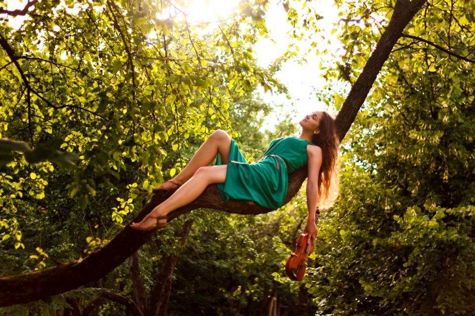 woman in green dress lying on tree branch