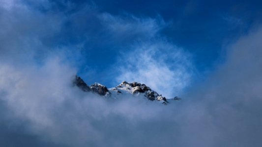 snow top mountain covered with fog during daytime