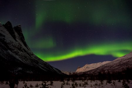 green aurora lights above snow-capped mountain photo