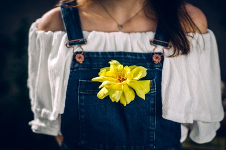 person wearing overalls with yellow petaled flowers on pocket