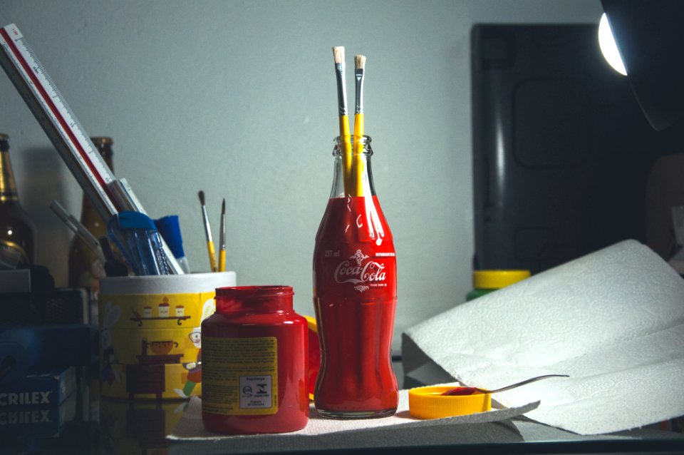 red Coca-Cola glass bottle with paint brushes