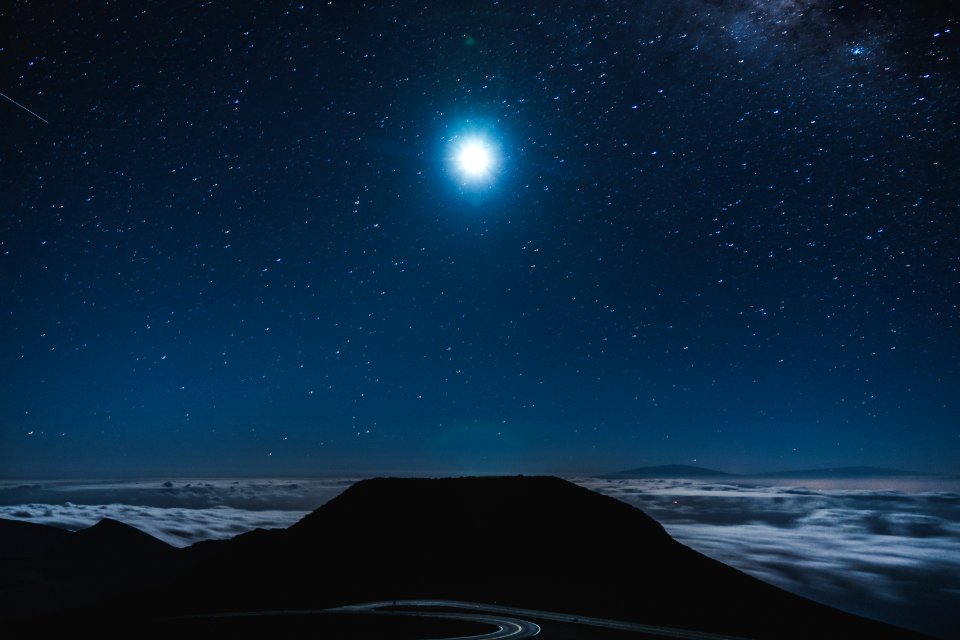 silhouette photo of body of water under blue sky at night