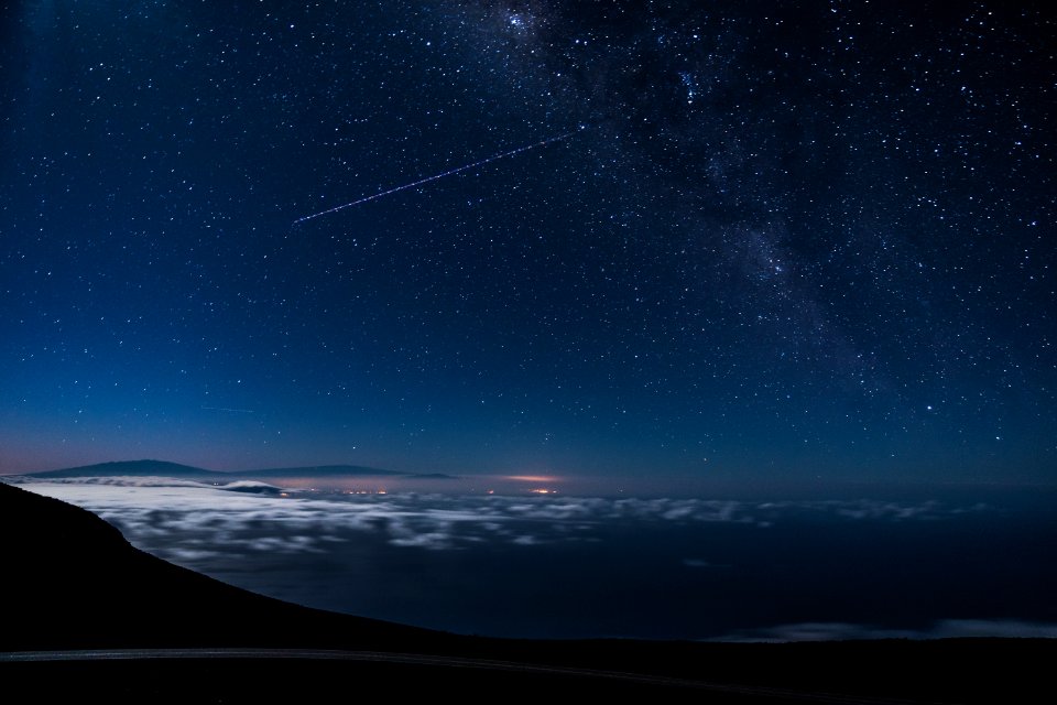 blue and black sky with stars and falling star at nighttime