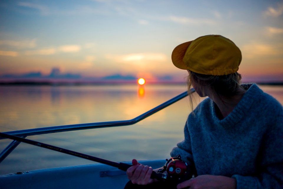 man holding black fishing rod while facing body of water photo