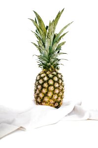 yellow and green pineapple fruit on white textile photo