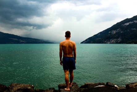 man wearing black shorts standing in front of body of water photo