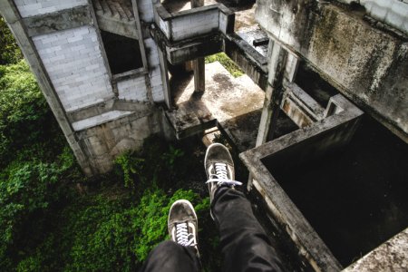 person sitting on gray abandoned building
