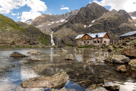 brown house near at body of water and surrounded by rocks during daytime photo