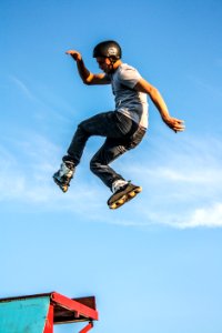 man in white t-shirt doing a roller skate trick in air photo