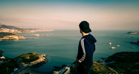 man standing on cliff near sea photo