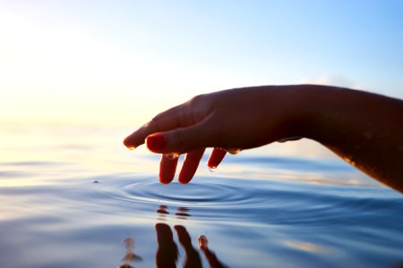 person about to touch the calm water photo