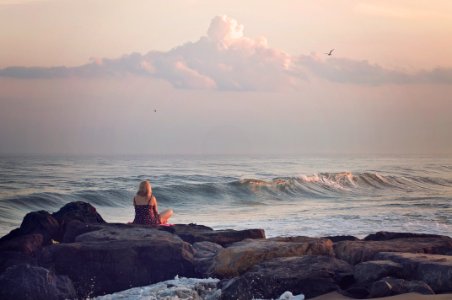 woman sitting on rock near body of water during daytime photo