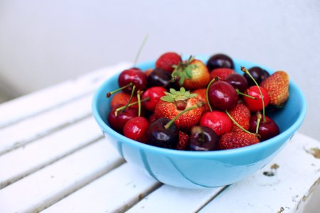focus photography of strawberries and cherries on blue bowl photo