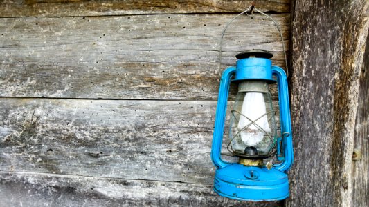 blue kerosene lamp hanging on wooden wall