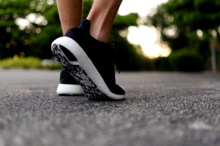 The sole of a pair of black and white shoes, taken from close up as someone lifts their foot to walk. photo