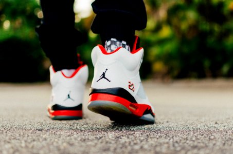 person wearing white, black, and red Air Jordan 5 shoes photo