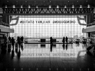 Black and white shot of station foyer with people and large window and reflection on floor photo