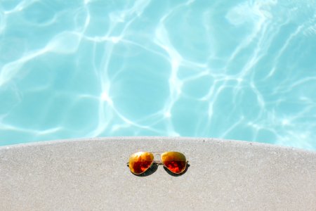 gold framed orange lens Aviator-style sunglasses beside pool photo