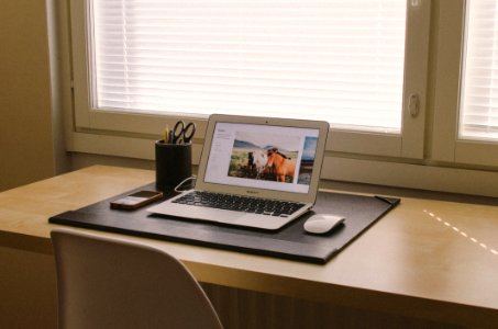 turned on MacBook on beige wooden desk photo