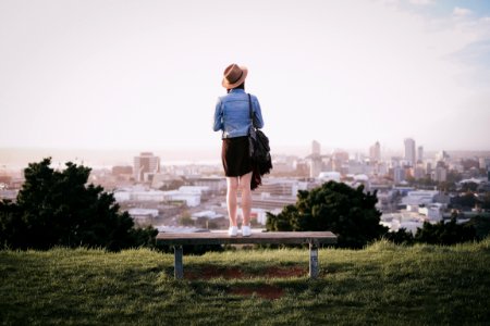 woman standing on bench facing city skyline during daytime photo