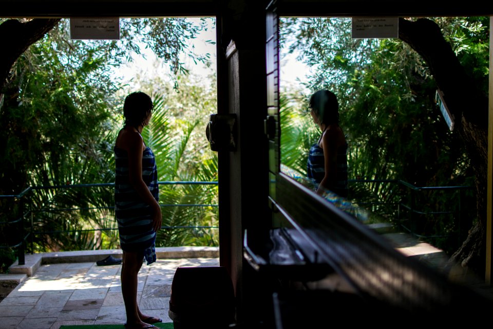 woman standing near door facing trees during daytime