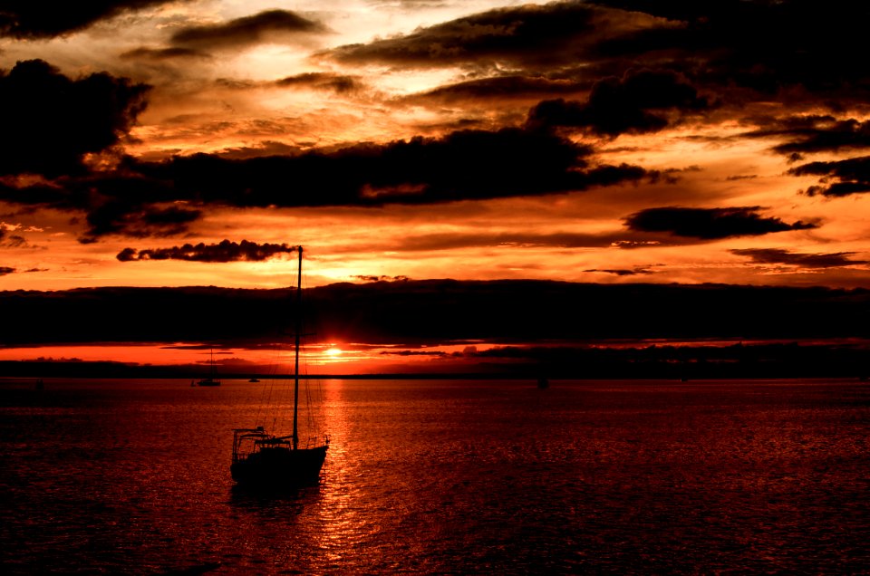 silhouette of boat on sea during golden hour