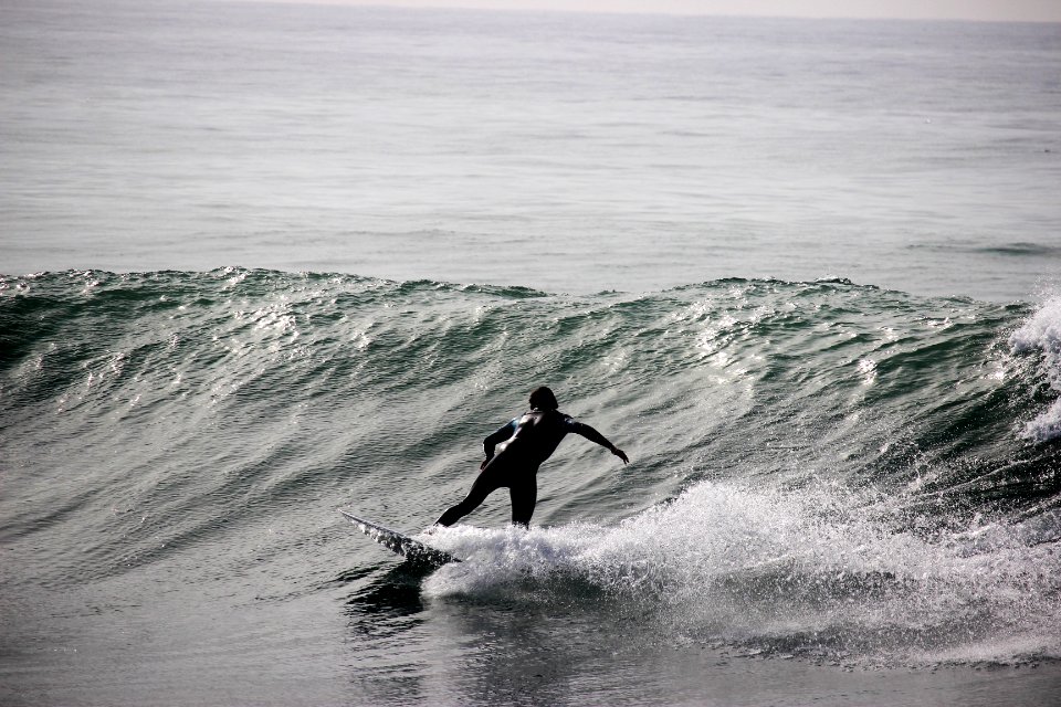 grayscale photography of surfer on body of water during daytime photo