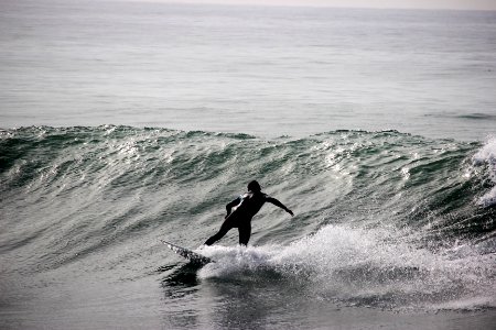 grayscale photography of surfer on body of water during daytime photo