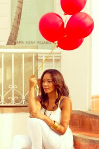 woman sitting on staircase while holding red balloons photo