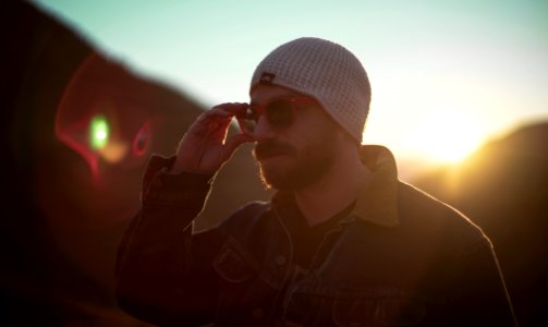 woman holding his sunglasses standing near mountain photo