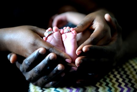 person touching baby's feet with two silver-colored rings