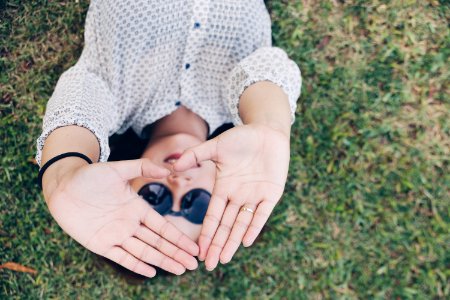 woman lying on grass forming her hands to triangle during daytime photo