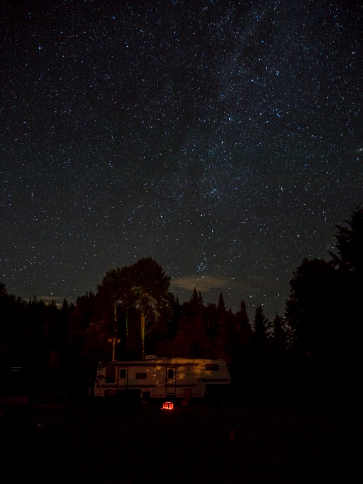 white RV trailer surrounded by trees during nighttime