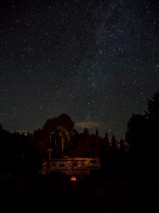white RV trailer surrounded by trees during nighttime