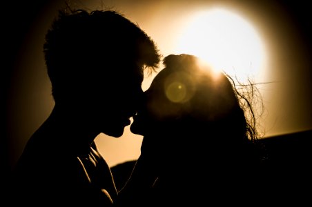 man and woman kissing under the sun photo