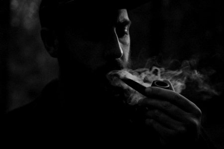 grayscale photo of man using smoking pipe